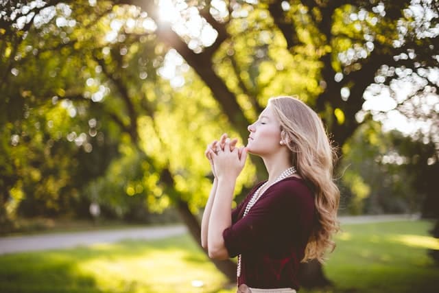 woman praying under tree
