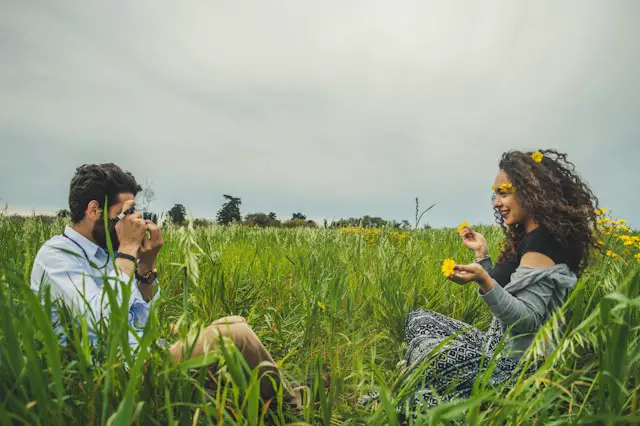 man taking photo of woman sitting on grass
